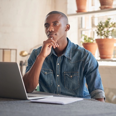 Thoughtful business man in office in front of laptop