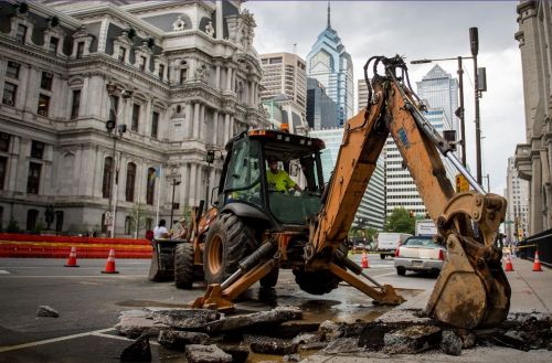 A backhoe operating in a downtown city setting.