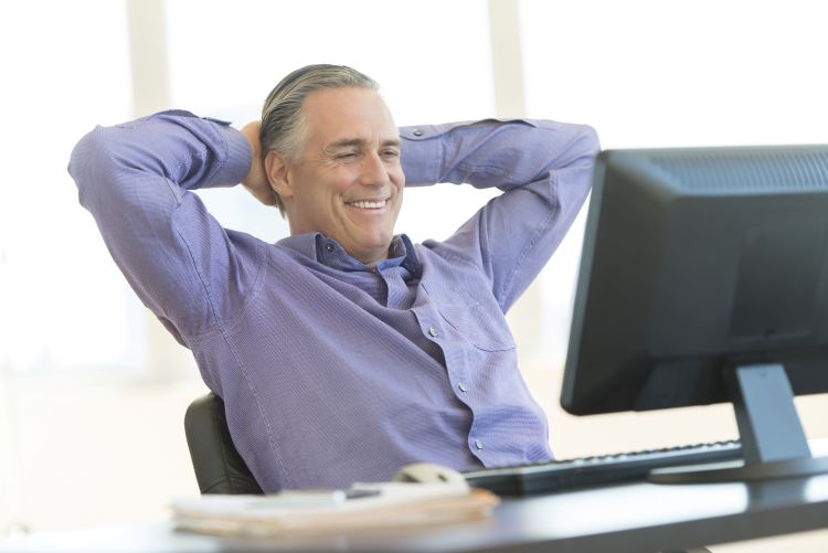 Businessman with Hands Behind Head Looking at Computer in Office